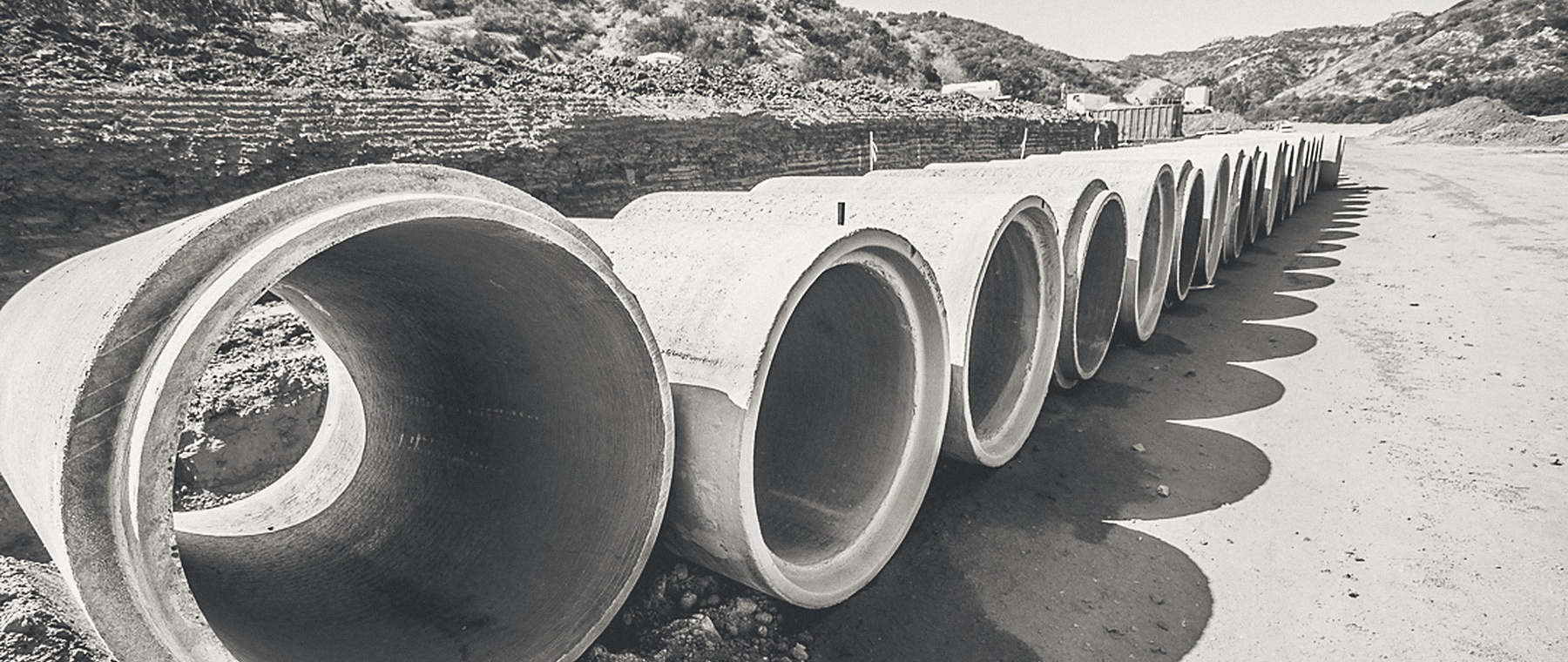 Storm drain pipe staged along a graded road